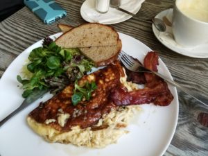 Breakfast with bacon, a burnt omelette, a salad and toast